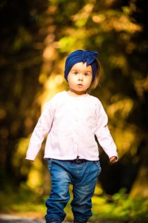 Portrait of 2 years old baby girl in forest walking by herself. Not wanting to follow parents.