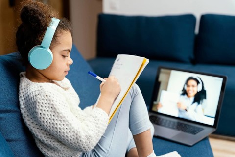 Side view little girl during online school with laptop headphones