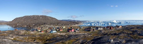 Rodebay, Greenland, July 09, 2018: Colorful wooden houses with icebergs in the background. Rodebay,