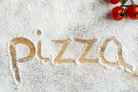 Top view pizza word written flour