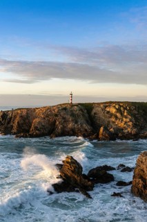 view of the rugged Alentejo coastline and Porto Covo lighthouse at sunset