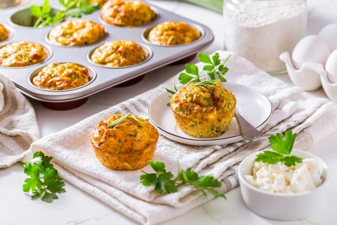 Delicious homemade zucchini muffins with feta cheese on white kitchen table