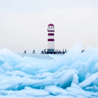 Lighthouse at jetty on the lake in winter