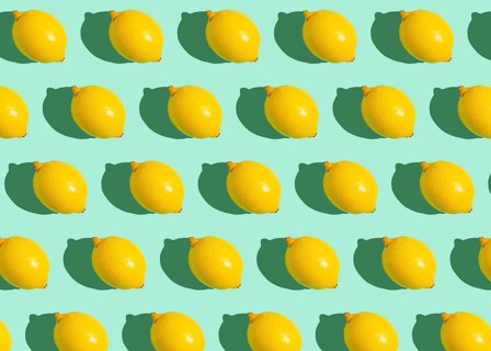 Fresh yellow whole lemons on minimal blue background on bright sun light with hard shadows pattern