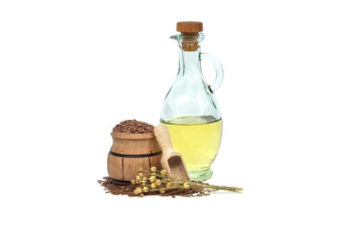 Linseed oil in glass decanter and linseed in wooden scoop near bunch of flax plants isolated on