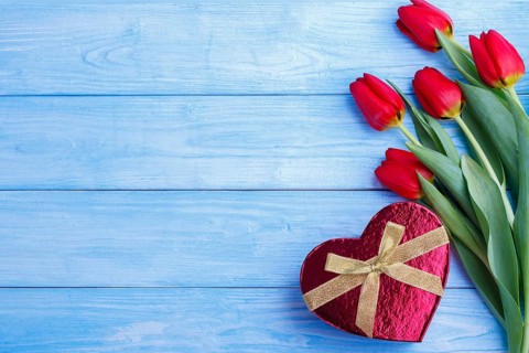 Bouquet of red tulips and gift box on rustic wooden board.copy space