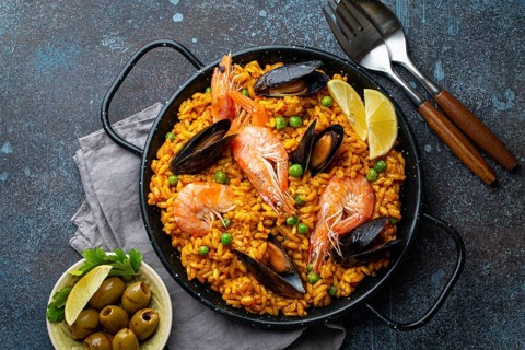 Classic dish of Spain, seafood paella in traditional pan on rustic blue concrete background top