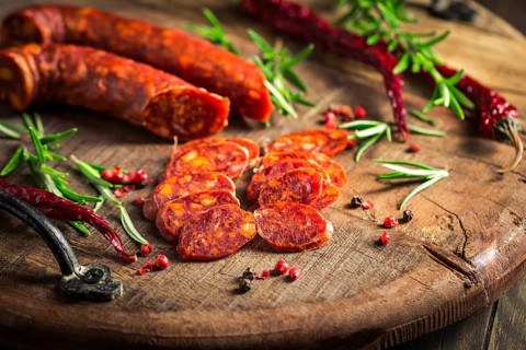 Red Spanish chorizo sausage with herbs and spices on wooden cutting board