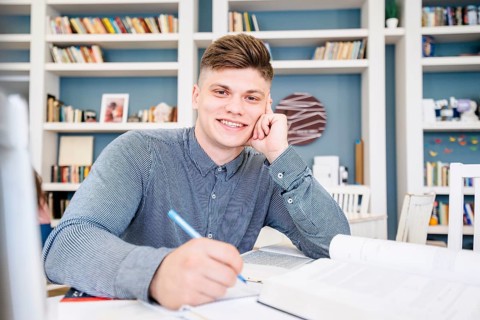 Student sitting with books pen library