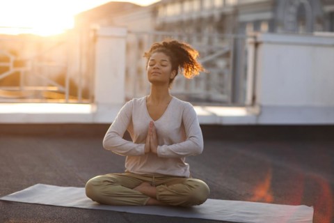 Cropped photo of woman sitting in lotus pose on mat and practicing yoga, female doing namaste