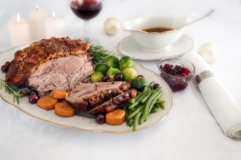 Roast pork ham with crust, green beans, Brussel sprouts, carrots, cranberry and sauce on white