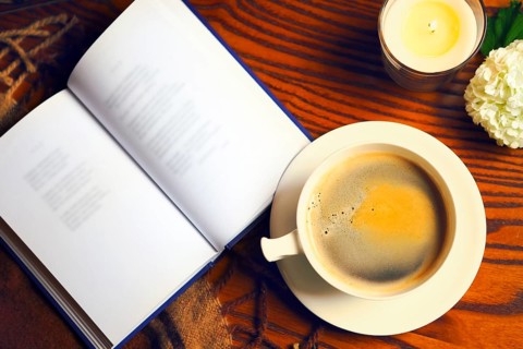Coffee, book, plaid and candle at home. Food, hygge and comfort concept