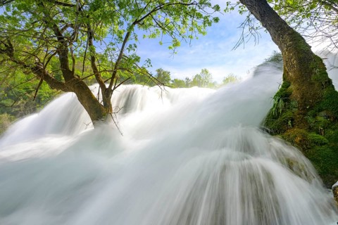 Dynamic water cascading powerfully through a green forest landscape, Krka National Park, Krka