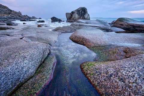 Rocks on beach of fjord of Norwegian sea in winteron sunset. Utakliev beach, Lofoten islands,