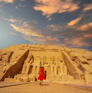 A European tourist in red dress walking towards the Abu Simbel Temple in southern Egypt in Nubia