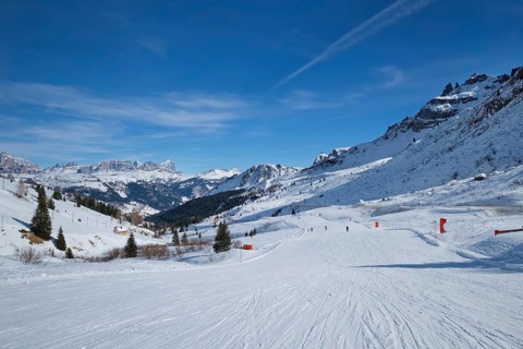 View of a ski resort piste with people skiing in Dolomites in Italy. Canazei, Italy, Europe