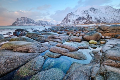 Rocks on beach of fjord of Norwegian sea in winteron sunset. Utakliev beach, Lofoten islands,