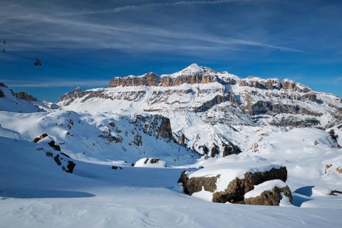 View of a ski resort piste with people skiing in Dolomites in Italy with cable car ski lift. Ski