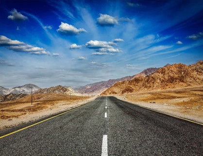 Travel forward concept background, road in Himalayas with mountains and dramatic clouds. Ladakh,