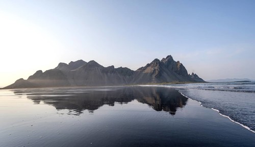 Black lava beach, sandy beach and sea, mountains Klifatindur reflected in the water, Eystrahorn and