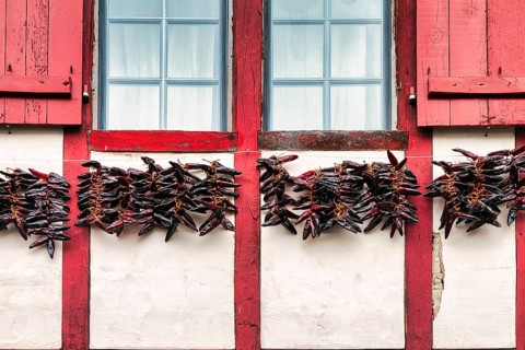 Chilli peppers, Piment dEspelette hanging to dry on facade, typical window with red shutters,