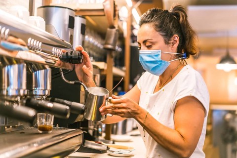 A waitress with a face mask in a bar. New normality, security measures after the coronavirus