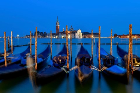 Venetian gondolas near St. Mark's Square in the evening light, blue hour, in the background the