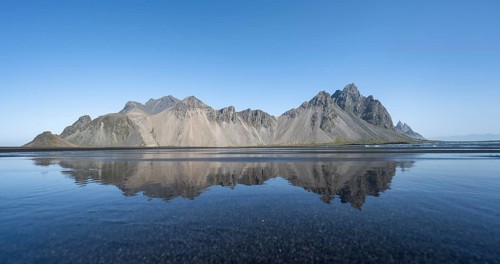 Black lava beach, sandy beach and sea, mountains Klifatindur reflected in the water, Eystrahorn and