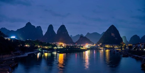 Panorama of Yangshuo town illuminated in the evening with dramatic karst mountain landscape in