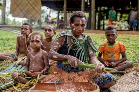 Local woman preparing banana leaves with roasted marrow of the Sago palm, village Pangoa, island