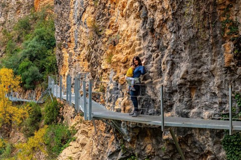 Very happy woman and son walking along the metal walkways of the Vero River path in Alquezar.