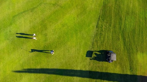 Aerial top view of three people on a green luxury gold course