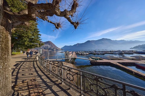 Lakeside promenade, lake, railing with decorations, sidelight, shadow, trees, hill, marina, blue