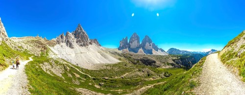 Panoramic. Hikers enjoying a sunny summer day on a scenic mountain trail near the iconic tre cime