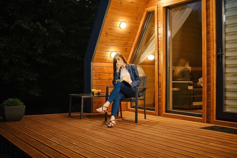 Late in the evening, a young woman sits on the terrace of a country house, eats an apple and reads