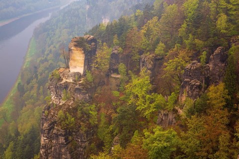 The bright lit Wartturm above the Elbe river seen from the Bastei rocks near the village of Rathen