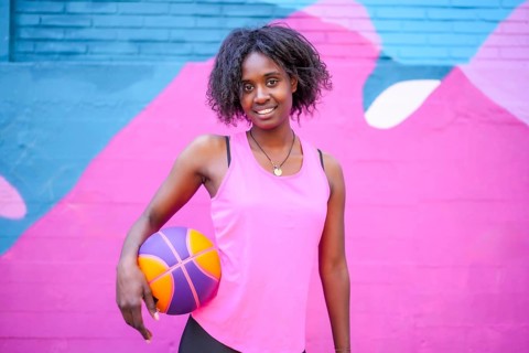 Portrait of a happy african female basketball player against colorful urban wall