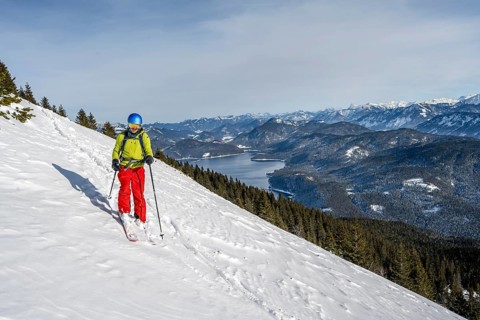 Skiers skiing down the Simetsberg, view of Walchensee and mountain panorama, Estergebirge, Bavarian