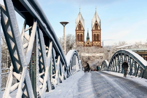 Bridge with snow and ice and cyclists, Blue Bridge and Stühlinger Church, Freiburg im Breisgau,