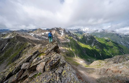 Mountaineer on a steep rocky ridge, on the summit of the Lasörling, view of mountains of the