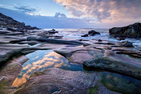 Rocks on beach of fjord of Norwegian sea in winteron sunset. Utakliev beach, Lofoten islands,