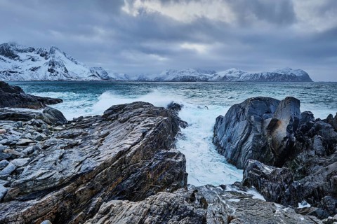 Waves of Norwegian sea crushing at rocky coast in fjord. Vikten, Lofoten islands, Norway, Europe