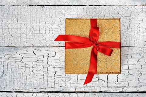 Gift birthday Christmas present concept, yellow gold gift box with red ribbon on white painted