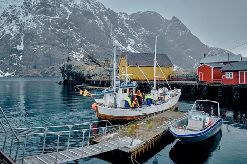 NUSFJORD, NORWAY, MARCH 25, 2017: Fishermen and fishing boat on pier in Nusfjord fishing village,