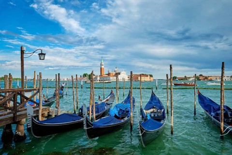 VENICE, ITALY, JUNE 27, 2018: Gondolas and gondolier in lagoon of Venice by Saint Mark (San Marco)