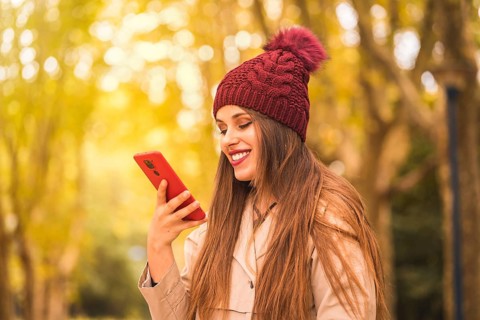 Portrait of a beautiful woman in autumn next to a forest in nature smiling sending a voice note