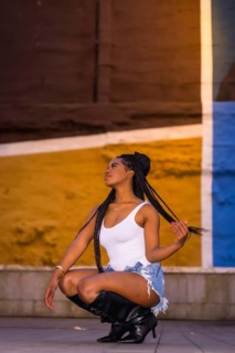 Fashionable urban style with an African girl with braids on a street in the city at night. White
