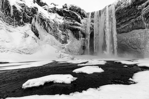 Skogafoss waterfall with icy and snowy rock face, black and white photo, Sudurland, Iceland, Europe