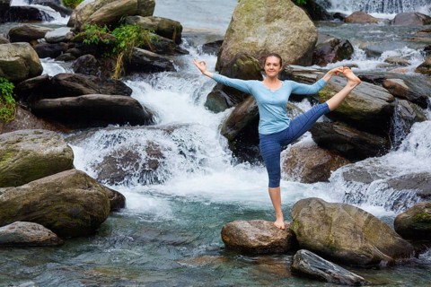 Yoga outdoors, woman doing Ashtanga Vinyasa Yoga balance asana Utthita Hasta Padangushthasana,