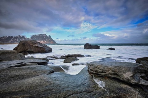 Rocks on beach of fjord of Norwegian sea in winter with snow. Utakliev beach, Lofoten islands,